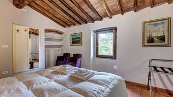 A bedroom with a large bed, a radiator, a window, and a door.