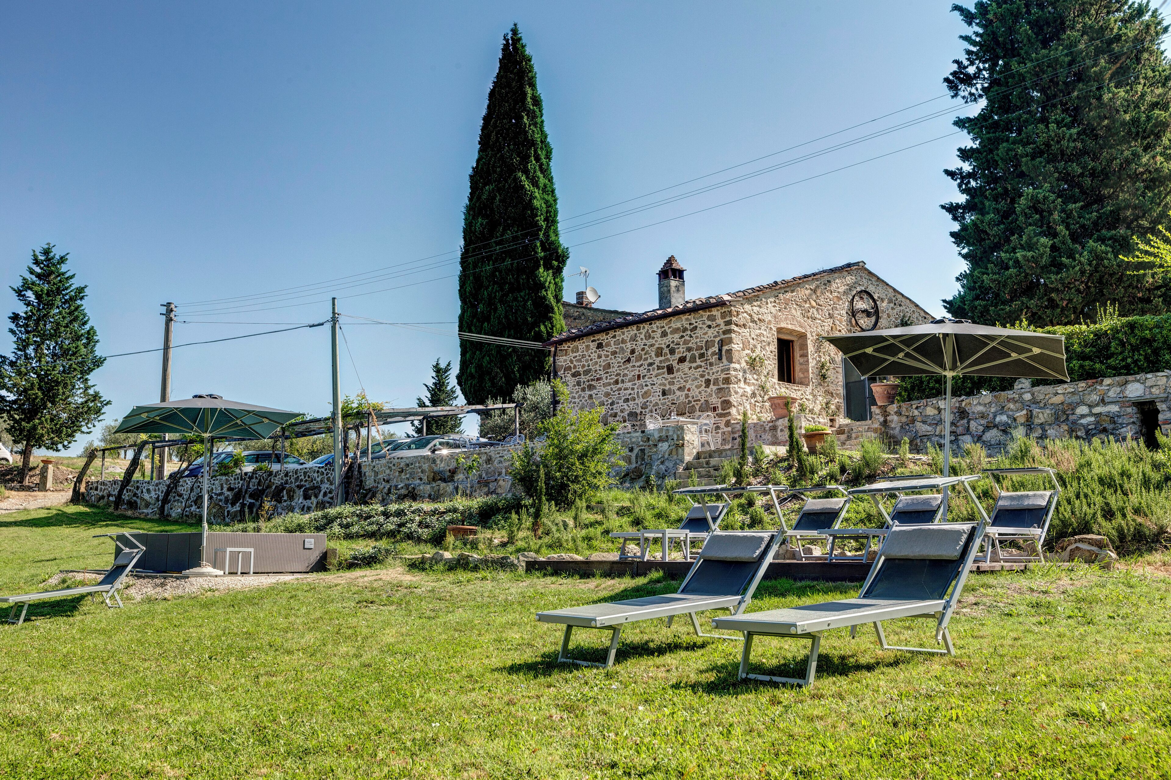 A stone building with a garden area featuring sun loungers and a stone wall.