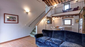 Una stanza con un divano blu, una scala e un'area pranzo con tavolo e sedie.