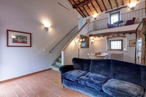 Una habitación con un sofá azul, una escalera y un comedor con una mesa y sillas.