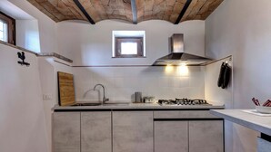Una cucina con isola centrale, piano cottura a gas, lavello e una finestra sopra il piano di lavoro.
