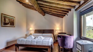 Una camera da letto con soffitto in legno, un letto con testiera, due lampade ai comodini, una sedia e una finestra vista.