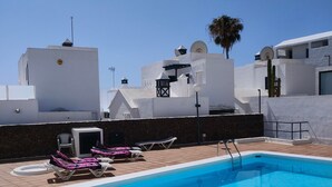 A swimming pool with a white border, surrounded by lounge chairs and a palm tree. - Casa Princesa, cerca de la playa grande de Puerto del Carmen  (Tías)