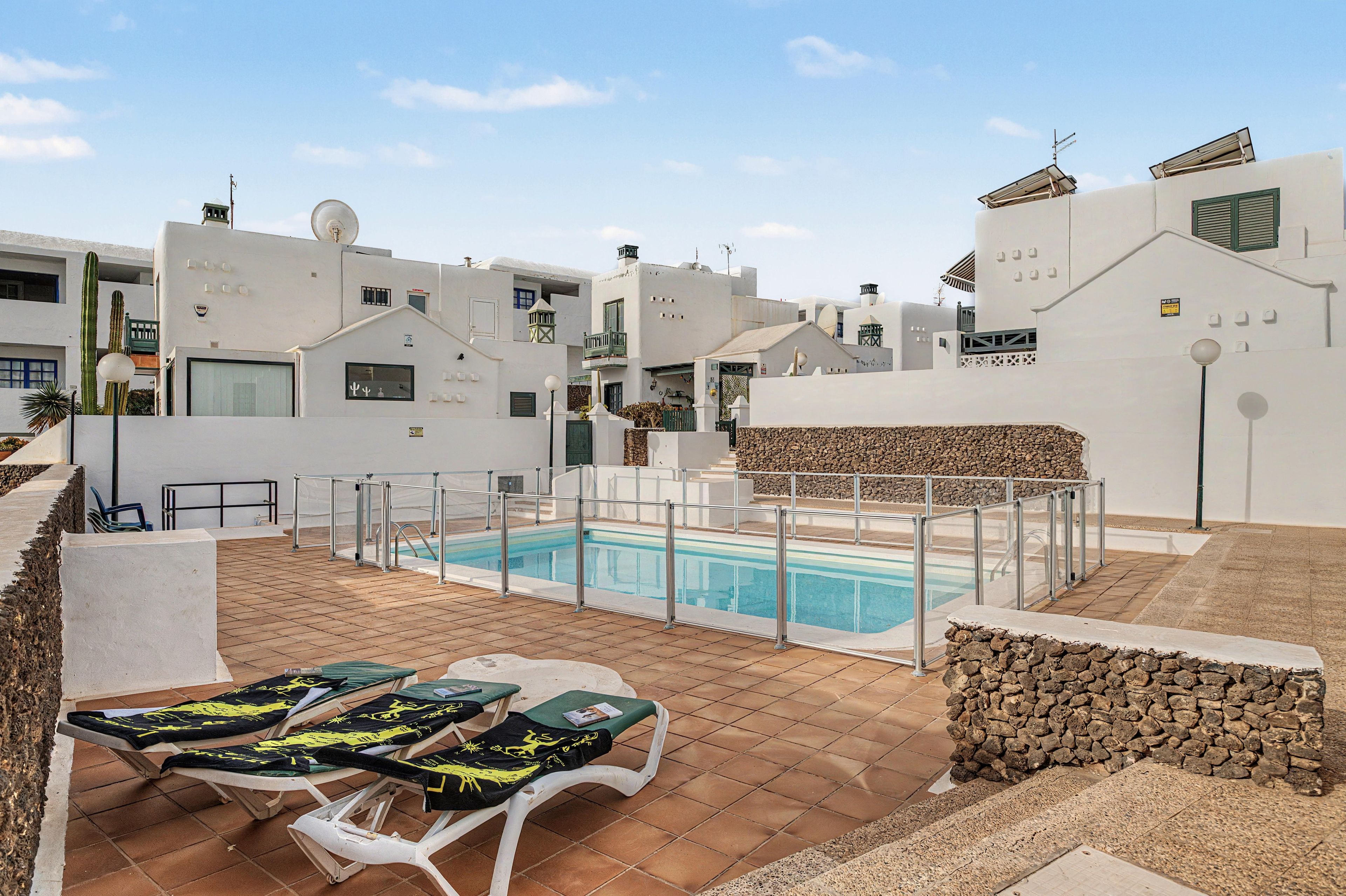 Un área de piscina en la azotea con sillones de descanso y una piscina.