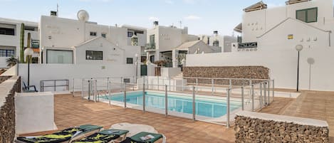 Un área de piscina en la azotea con sillones de descanso y una piscina.