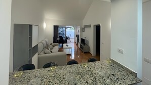 A modern kitchen with a granite countertop and a dining area with a table and chairs. - Casa Princesa, cerca de la playa grande de Puerto del Carmen  (Tías)