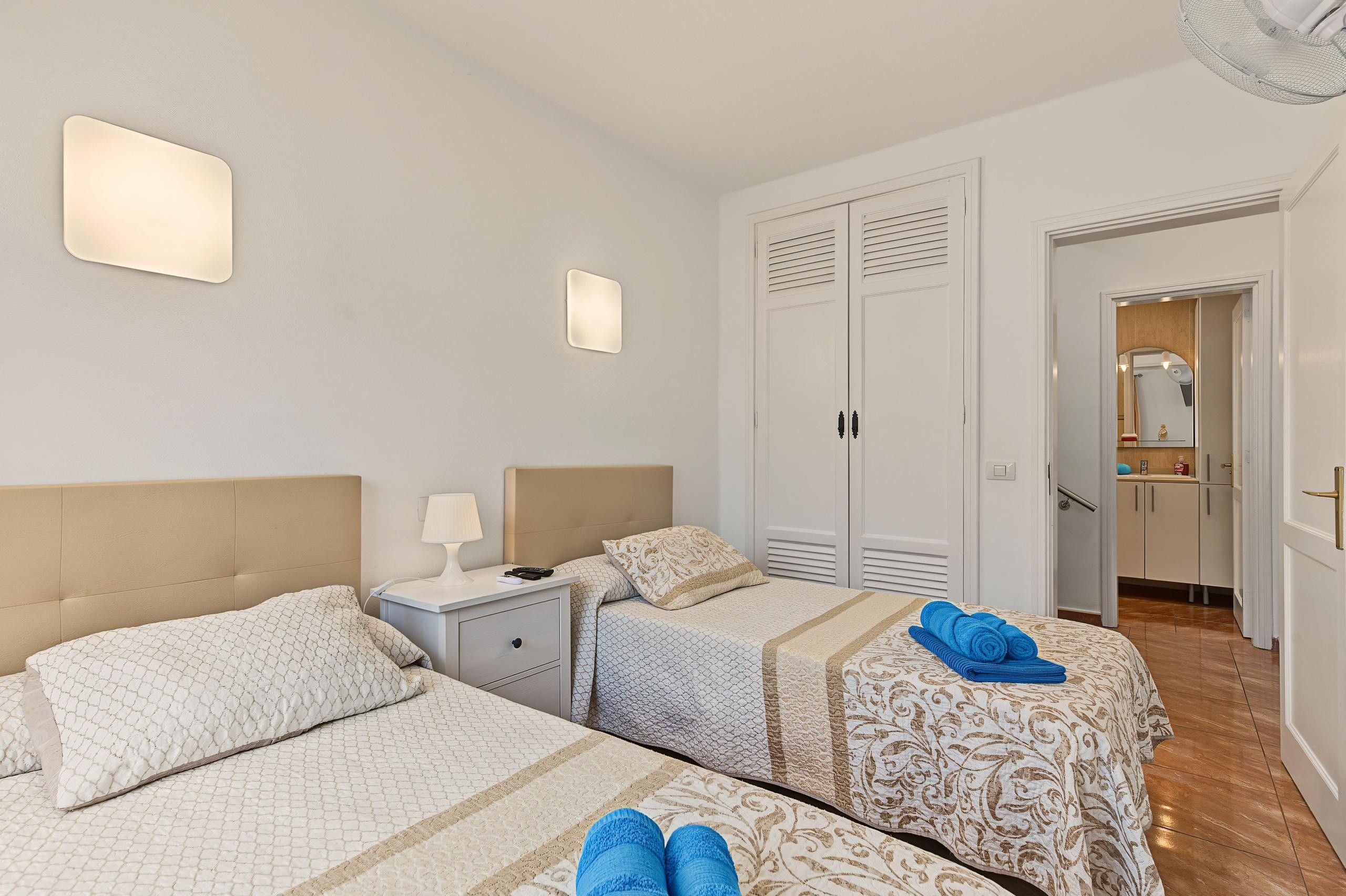 Ein Hotelzimmer mit zwei Betten, einem Nachttisch, einer Lampe und einem Spiegel.