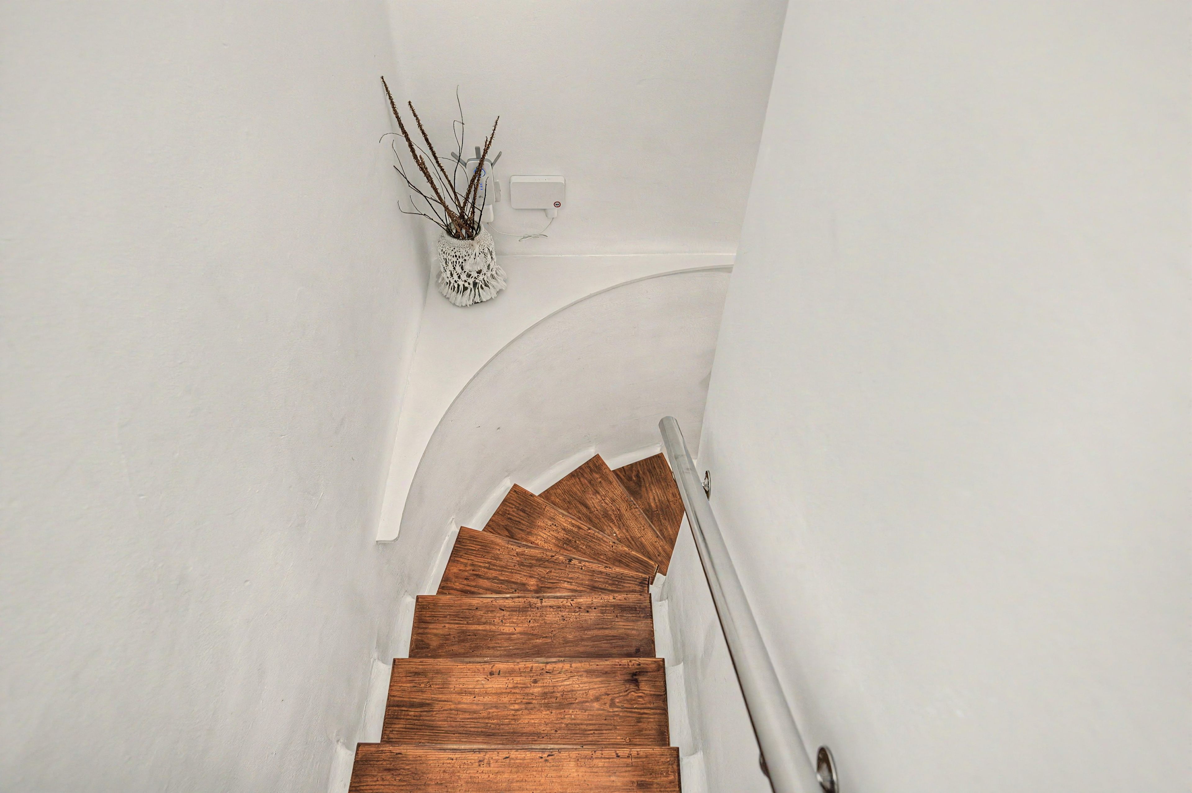 A wooden staircase with a white wall and a white wall-mounted light fixture.