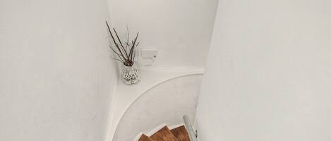 A wooden staircase with a white wall and a white wall-mounted light fixture.