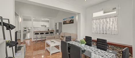 A modern living space with a dining area, kitchen, and a view of the outdoors.