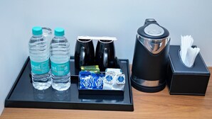Een dienblad met twee waterflesjes, een zonnebril, een koffiezetapparaat en een zakdoos.