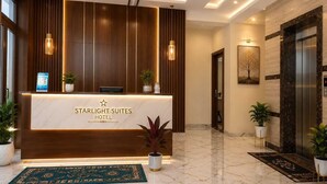 Een hotel receptie met een marmeren vloer, houten lambrisering en een receptiebalie met een bord waarop staat: 'STARLIGHT SUITES HOTEL'.