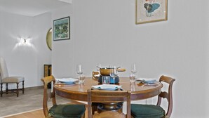 A dining room with a round table, chairs, and a painting on the wall. - Renovated apartment, large balcony, 10 minutes from the slopes (Crans-Montana)