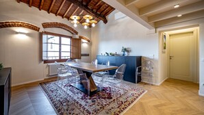 A spacious dining area with a wooden table and chairs, a patterned rug, and a kitchen area with cabinets and a refrigerator. - Luxury Duomo apartment (Florence)