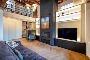A modern living room with a sofa, a fireplace, and a staircase leading to an upper level. - Luxury Duomo apartment (Florence)