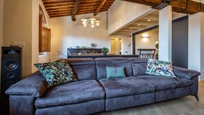 A modern living room with a leather sofa, wooden beams, and a kitchen in the background. - Luxury Duomo apartment (Florence)