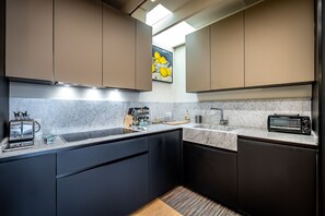 A modern kitchen with dark cabinets, a marble countertop, a toaster, and a sink. - Luxury Duomo apartment (Florence)