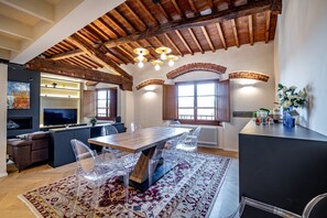 Een moderne keuken met een houten plafond, een eethoek met transparante stoelen, en een groot raam.