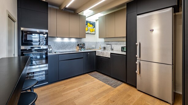 A modern kitchen with stainless steel appliances, dark cabinetry, and a marble countertop. - Luxury Duomo apartment (Florence)