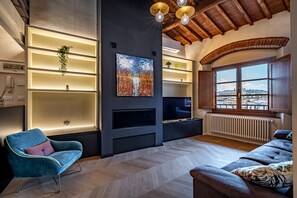 Een moderne woonkamer met een open haard, een blauwe fauteuil, een bank en een groot raam met uitzicht.
