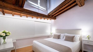 A modern bedroom with a large bed, bedside tables, a nightstand, and a skylight. - Luxury Duomo apartment (Florence)