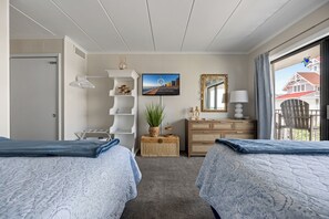 Ein Hotelzimmer mit zwei Betten, einem Schminktisch, einem Spiegel, einem Fernseher und Blick nach draußen.