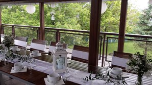 An outdoor dining area with tables set for a meal, surrounded by a wooden pergola and a view of greenery. - Hotel Preveza (Spišská Nová Ves)