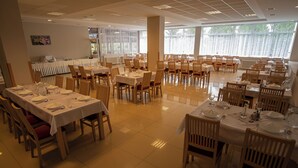A spacious dining area with multiple tables set for service, large windows providing natural light, and a clean, tiled floor. - Hotel Preveza (Spišská Nová Ves)