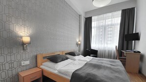 A modern bedroom with a bed, bedside tables, a desk, and a TV. - Hotel Preveza (Spišská Nová Ves)