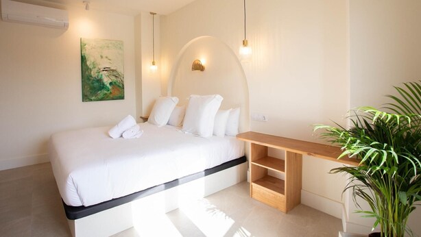 A bedroom with a bed, bedside table, and a potted plant. - Standard double Mercado apartment with jacuzzi (Alicante)