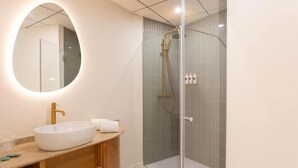 A modern bathroom with a round mirror, a white sink, and a glass-enclosed shower area. - Standard double Mercado apartment with jacuzzi (Alicante)