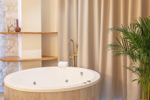 Une salle de bain avec une baignoire sur pieds, une serviette, une étagère avec des objets décoratifs et une plante en pot.