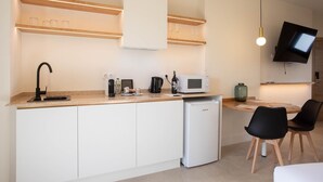 A modern kitchen with a built-in dishwasher, a microwave, and a coffee maker. There is a dining area with a table and chairs. - Standard double Mercado apartment with jacuzzi (Alicante)