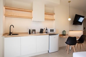 A modern kitchen with a built-in dishwasher, a microwave, and a coffee maker. There is a dining area with a table and chairs. - Standard double Mercado apartment with jacuzzi (Alicante)