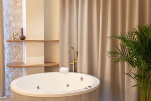 A bathroom with a freestanding bathtub, a towel rack, and a shelf with decorative items.