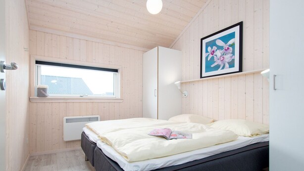 Um quarto com uma cama, janela, radiador e um quadro na parede.