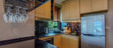 Une cuisine moderne dotée d’un réfrigérateur encastré, de meubles en bois et d’un plan de travail noir.