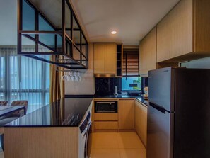 A modern kitchen with a central island, stainless steel appliances, and wooden cabinetry. - Luxurious 2BR Condo With Ocean Views in Choeng Thale (Choeng Thale)