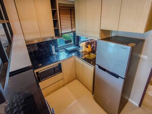A compact kitchen with a built-in refrigerator, a microwave, and a sink. - Luxurious 2BR Condo With Ocean Views in Choeng Thale (Choeng Thale)