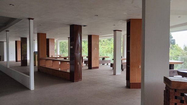 Um espaço amplo e interno, com pé direito alto, pilares de madeira e um balcão central.