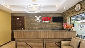 A reception area with a wooden reception desk, a clock, and a TV mounted on the wall.