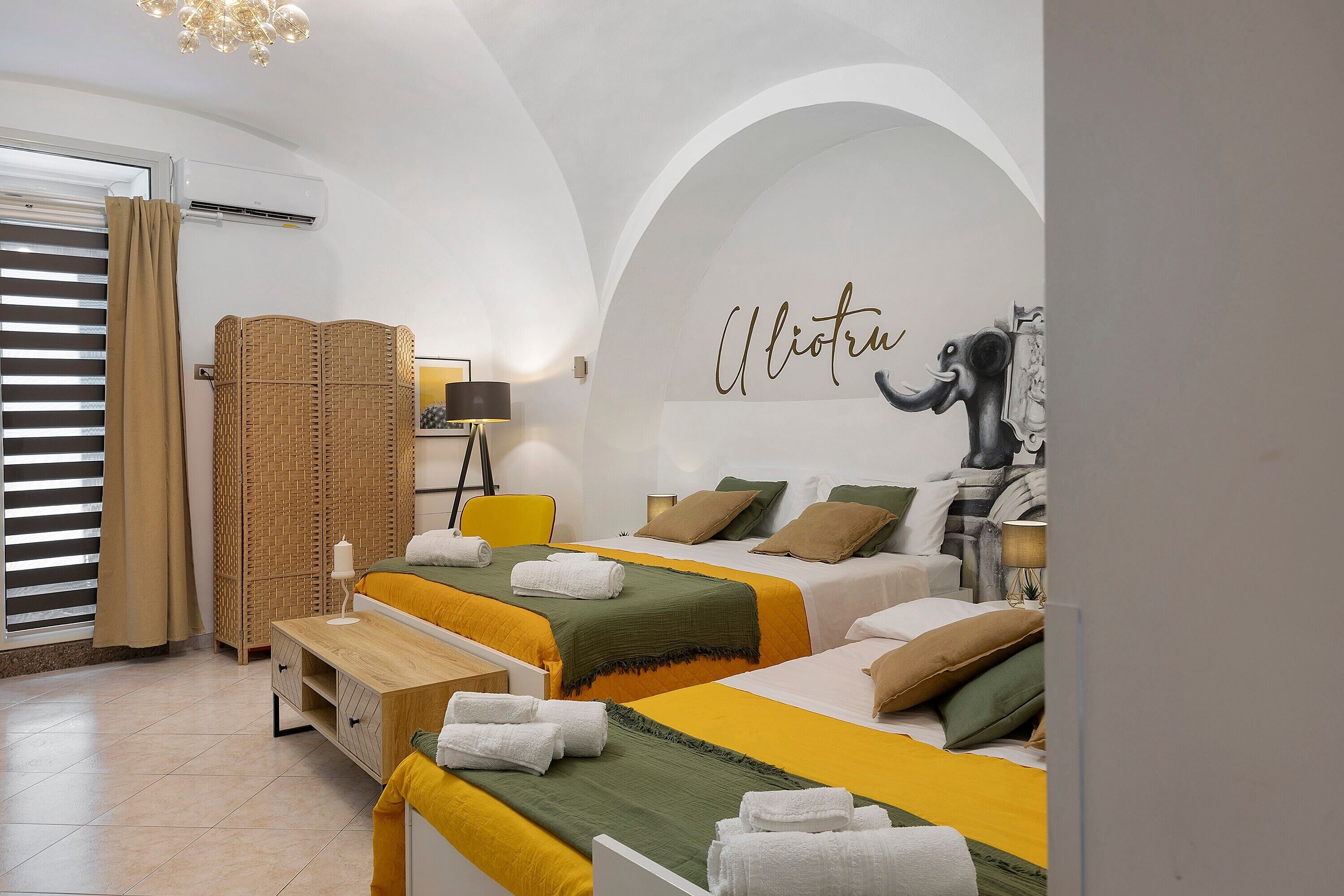 A hotel room with two beds, a large mirror, and a decorative elephant sculpture.