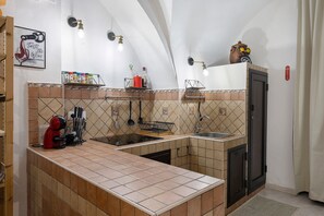 Una cucina con piastrelle a mosaico, un lavandino, un fornello e diversi utensili da cucina.