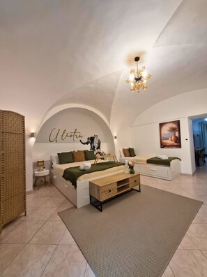 Een ruime slaapkamer met een groot bed, een nachtkastje, een bankje en een kunstwerk aan de muur.