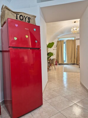 Ein roter Kühlschrank mit herzförmigen Magneten und einem Schild mit der Aufschrift 'TOYS'.