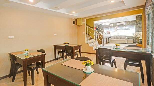 Uma sala de jantar de hotel com mesas e cadeiras, uma escadaria que leva a uma sala de estar e vista para o exterior.