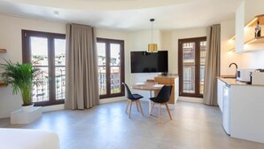 Una sala de estar moderna con comedor, un televisor de pantalla plana y una cocina con microondas.