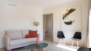 Una sala de estar moderna con un sofá, dos sillones, una mesita de centro y un cuadro en la pared.