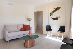 Ein modernes Wohnzimmer mit Sofa, zwei Sesseln, einem Couchtisch und einem Bild an der Wand.