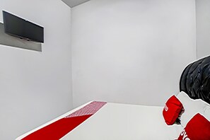 A minimalist room with a bed, a flat-screen TV mounted on the wall, and a red and white patterned bed runner. - Hotel O Brayan | Cozy Single Room (Medan)